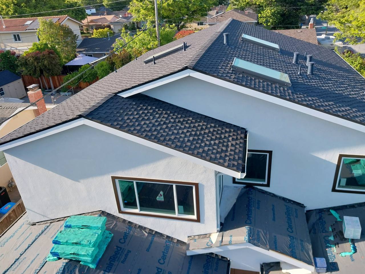 Aerial view of completed Charcoal roof with skylights and tree-lined San Jose street in the background